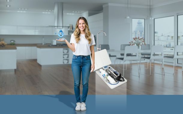 Sistema Home Water System Acquaviva per la microfiltrazione dell&rsquo;acqua domestica con ragazza in cucina e dispositivo sottolavello plastic free
